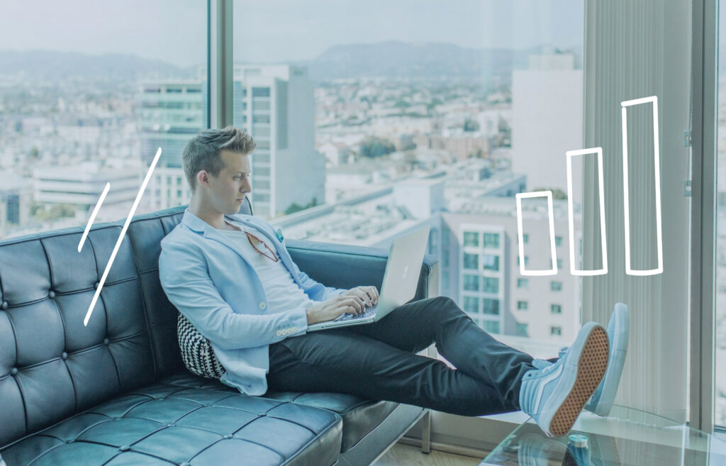 Person working on a laptop on a couch in a modern apartment with city views, with simple bar chart graphics overlayed.