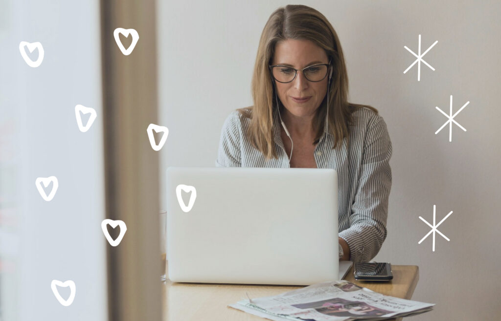 Person working on a laptop at a table with phone and papers, with decorative heart and star doodles overlayed.