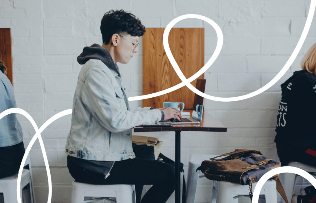 Person working on a laptop at a café table with a coffee mug, with abstract white line graphics overlayed.