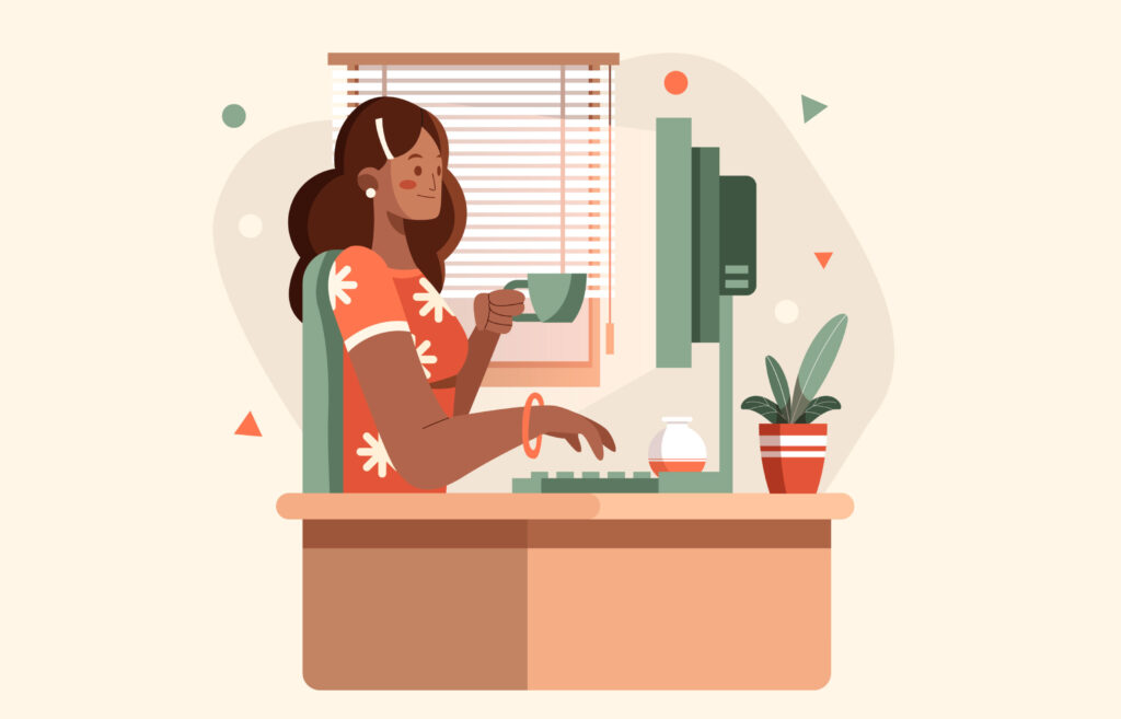 Woman sitting at a computer holding a mug and typing