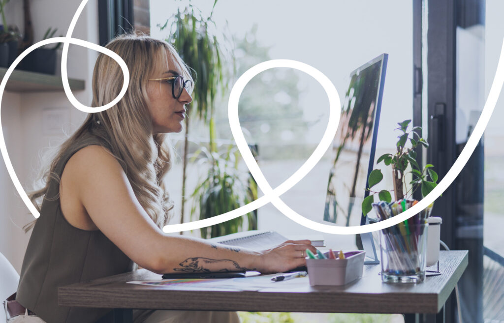 A woman with glasses works at a computer in a bright, plant-filled workspace, with white looping graphic lines overlaying the image to suggest creativity or flow.